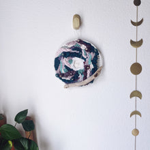 Load image into Gallery viewer, handcrafted 10" round woven wall hanging with lavender, mint, eggplant, teal and creamy white accented with driftwood and hung from a bronze hook.