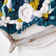 Load image into Gallery viewer, Close up of handcrafted 12" round wall hanging with teal, aqua, seafoam, navy, pistachio and creamy white natural fibers accented by driftwood