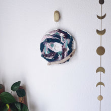Load image into Gallery viewer, handcrafted 10&quot; round woven wall hanging with lavender, mint, eggplant, teal and creamy white accented with driftwood and hung from a bronze hook.
