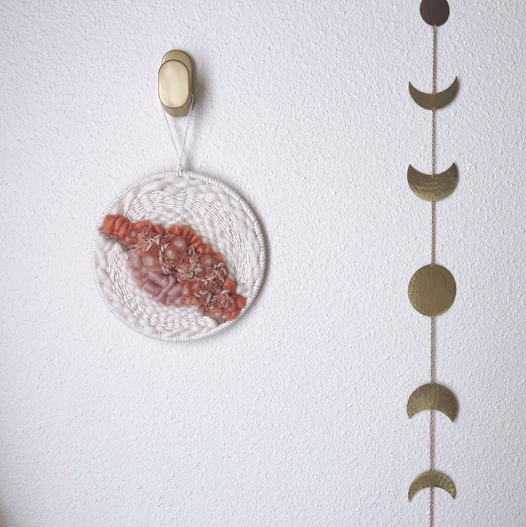 handcrafted round woven wall hanging with peach, coral and dusky rose, sand and cream wool and natural fibers